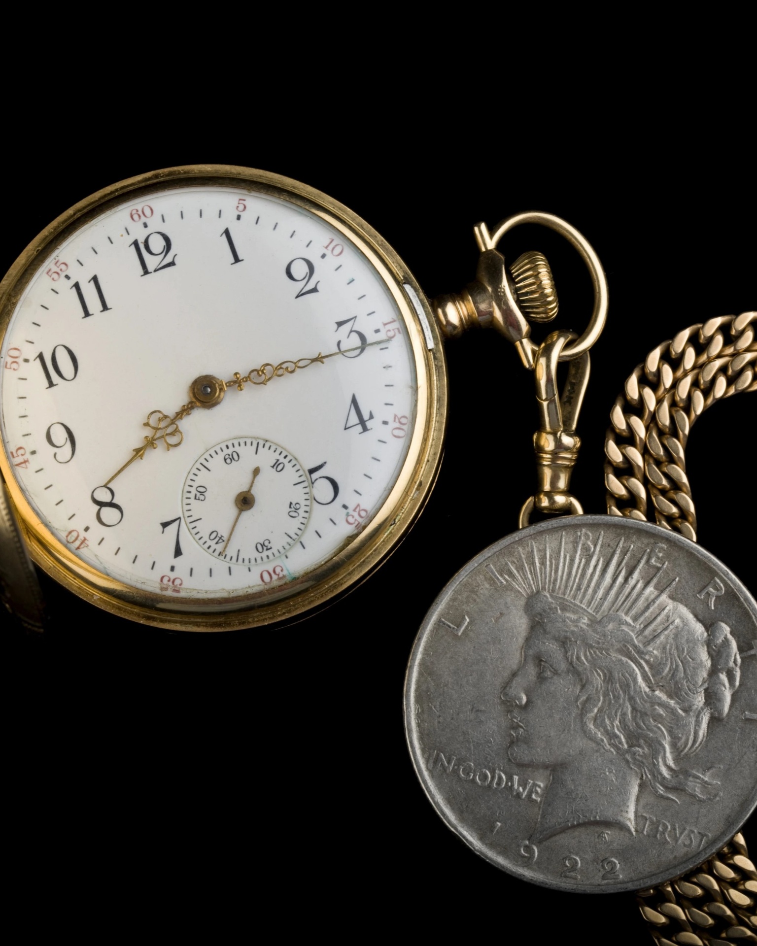 Antique pocket watch with Peace Dollar on black background